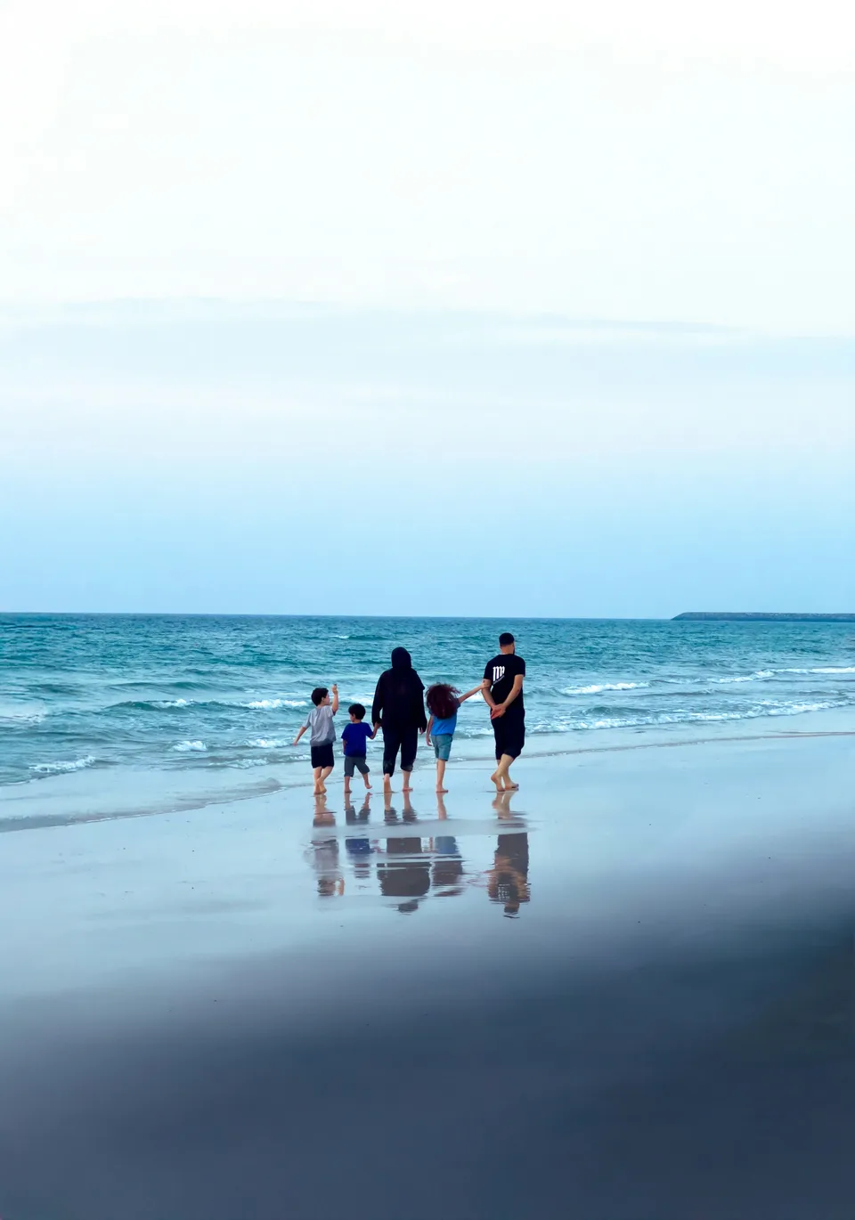 A family holding hands as they walk towards the sea