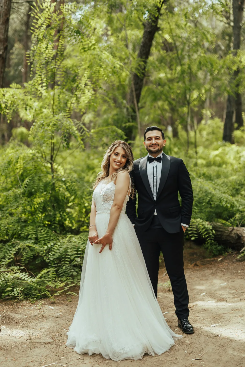 A wedding couple walking together beneath the trees